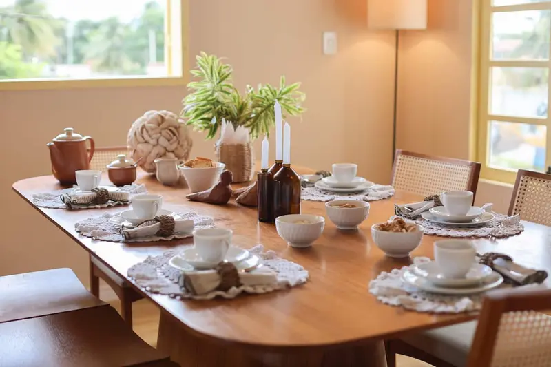 Mesa comprida com louça de cerâmica e guardanapos de tecido