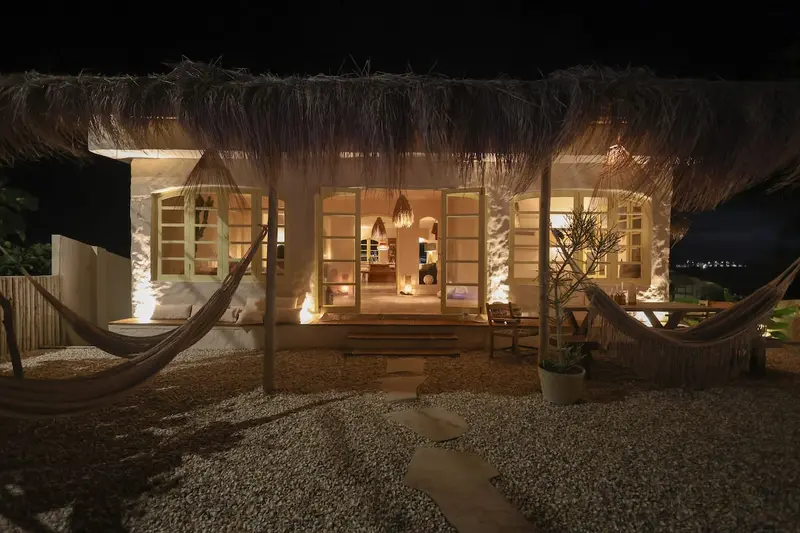Casa iluminada à noite, com redes no terraço