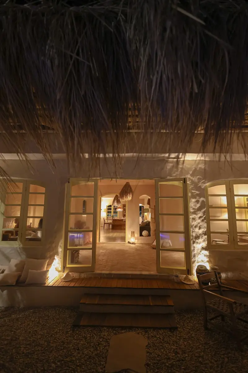 Entrada da casa iluminada, sob o telhado de palha