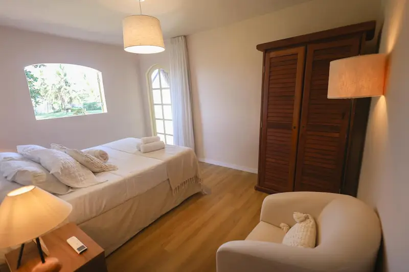 Quarto 1 com cama de casal e poltrona, janelas em arco