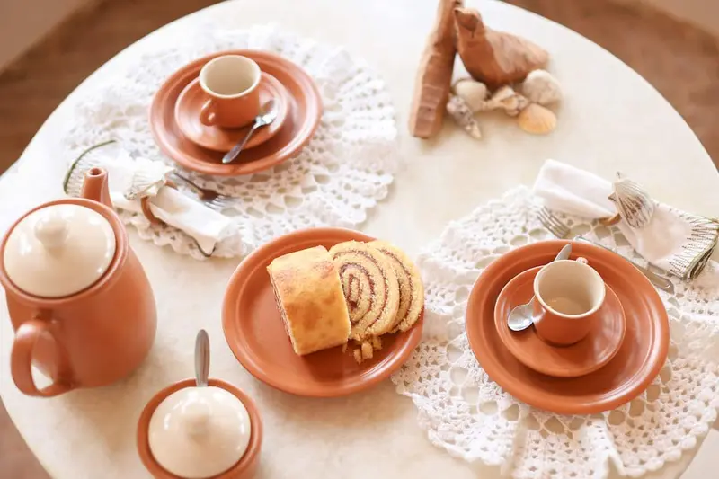 Mesa de café da manhã com cerâmica, bolo e rendas