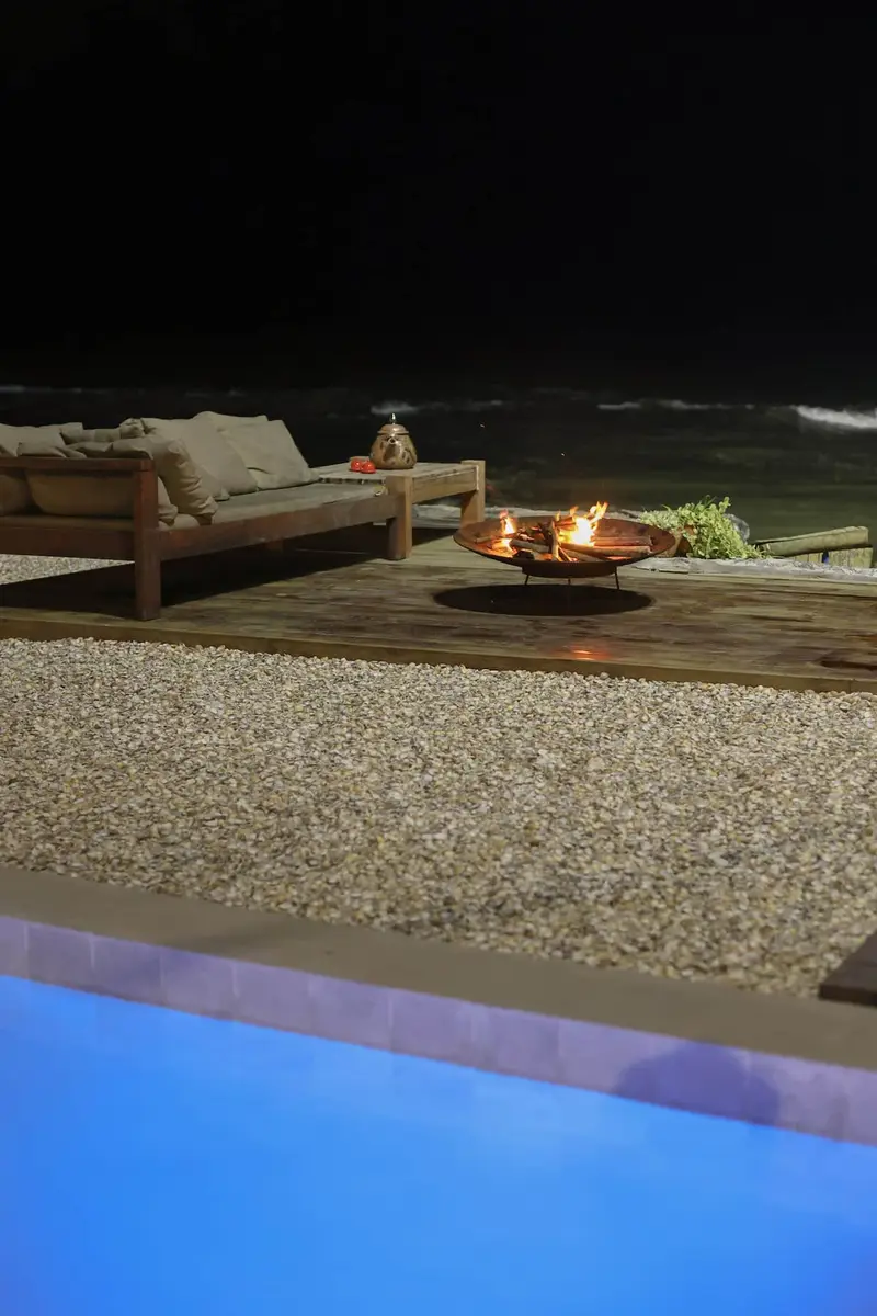 Deck à noite, com a fogueira acesa ao lado da piscina iluminada