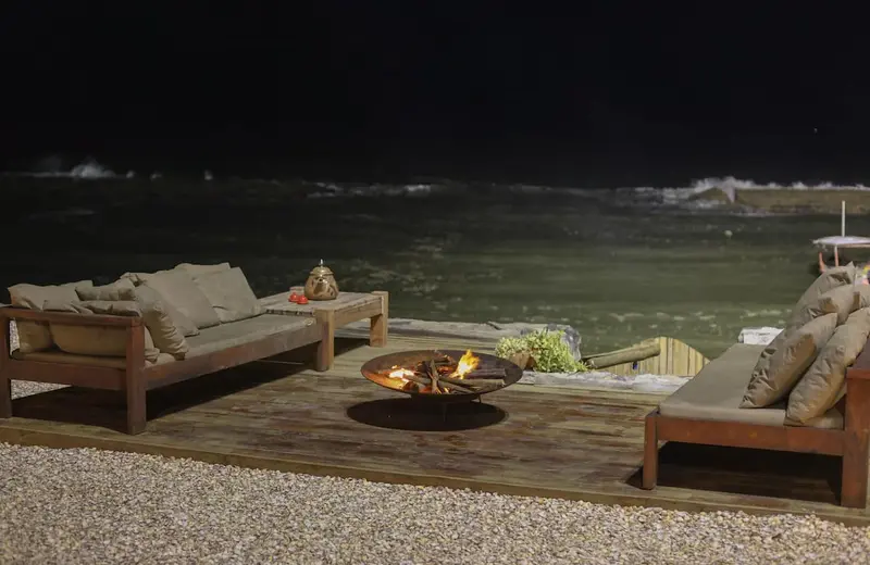 Deck à noite com a fogueira e o mar escuro ao fundo