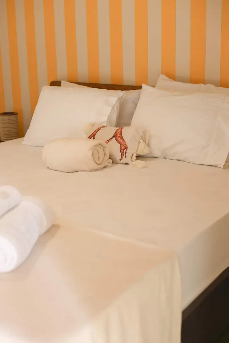 Cama do Quarto 4 com travesseiros e toalhas enroladas