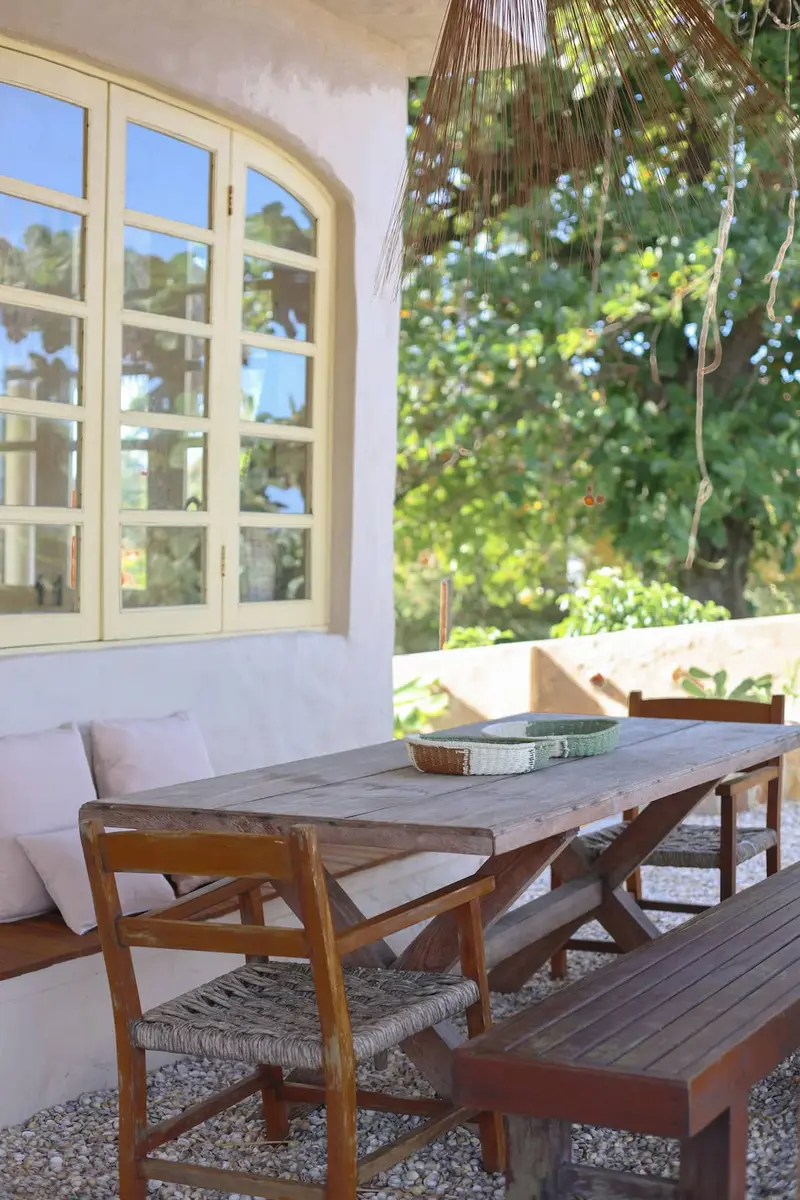Mesa de madeira e bancos no deck, junto às portas amarelas