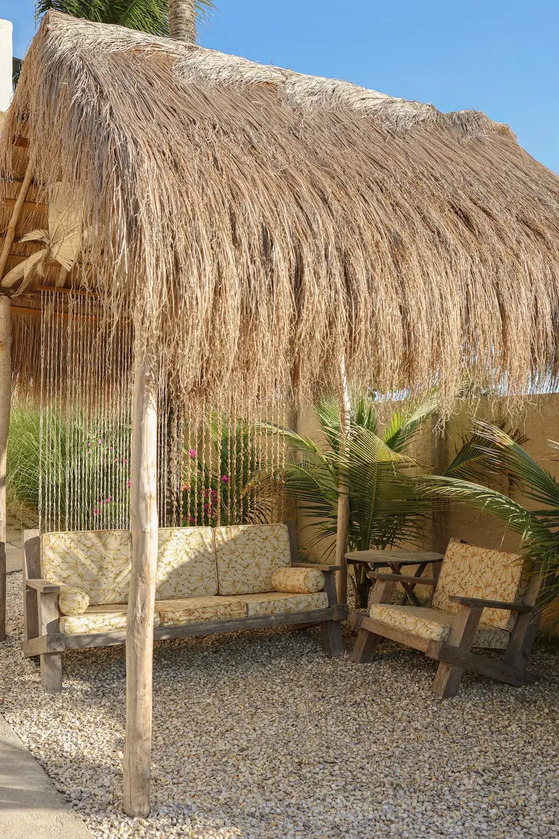 Gazebo de palha com sofá e poltronas de madeira