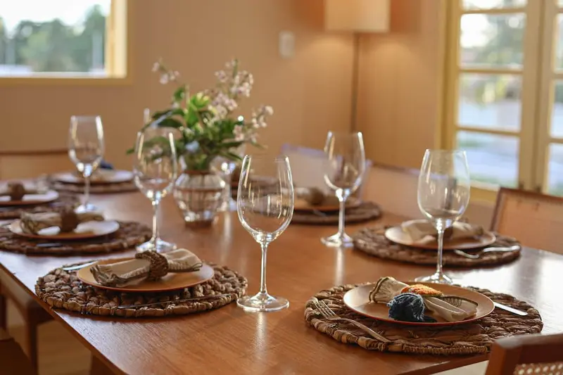 Mesa de jantar posta com taças e flores, sob as janelas em arco